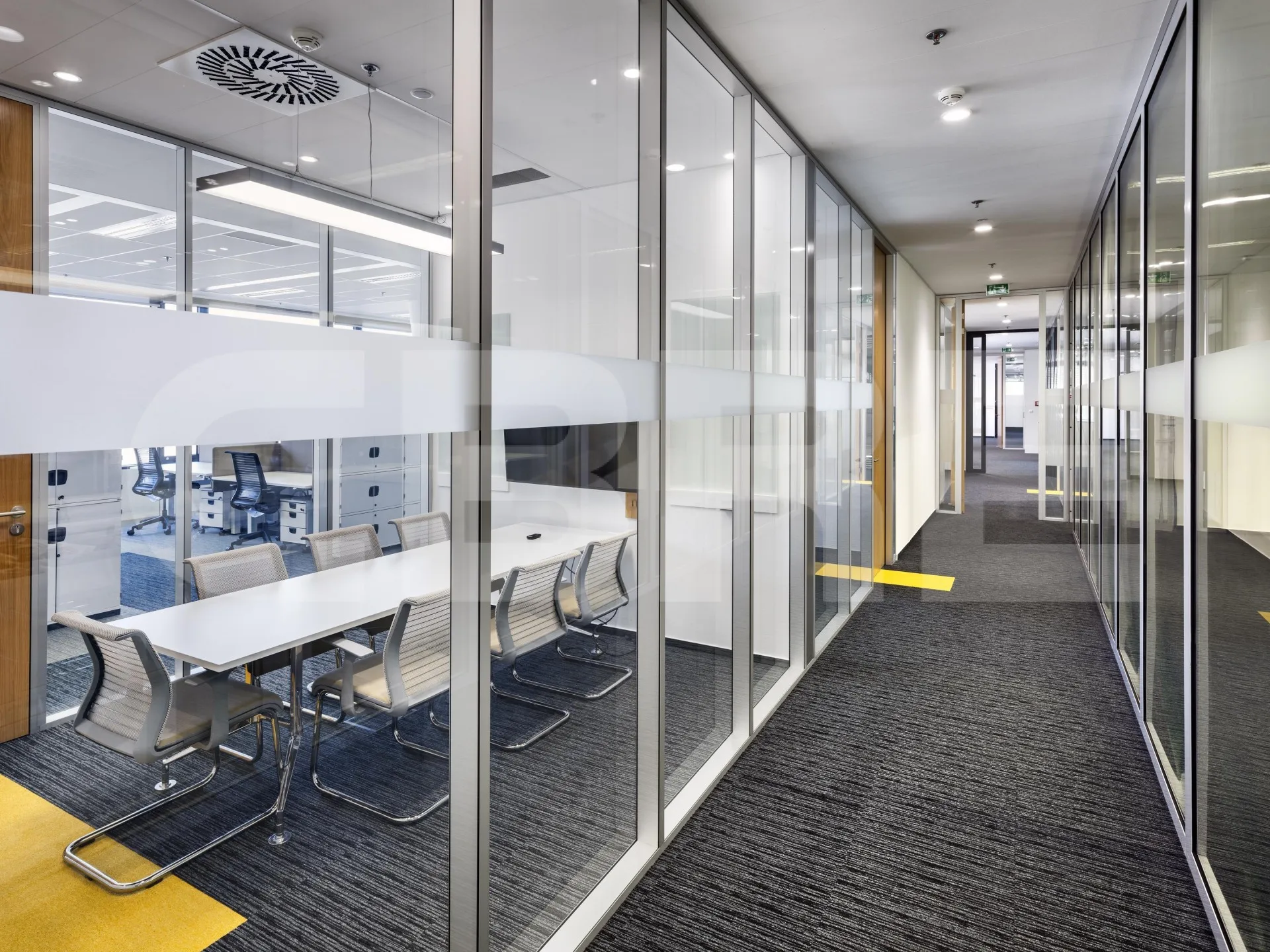 Glass-walled meeting room and corridor inside the office
